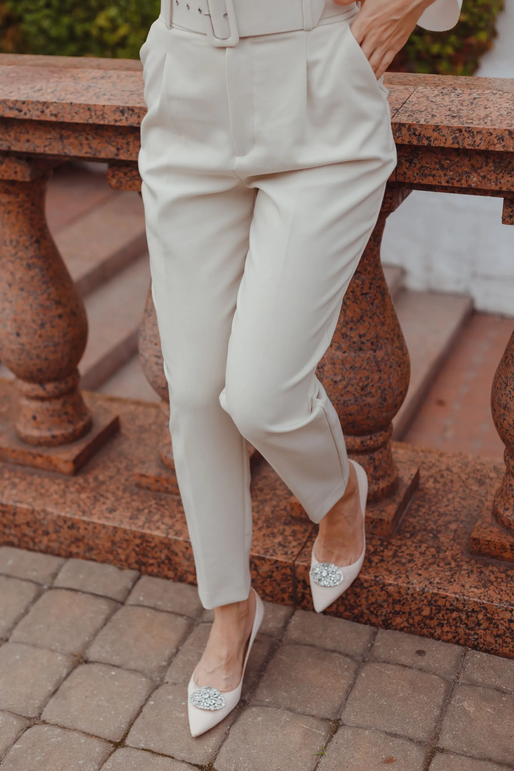 Cream tailored trousers worn with pale pointed shoes, seen from the waist down