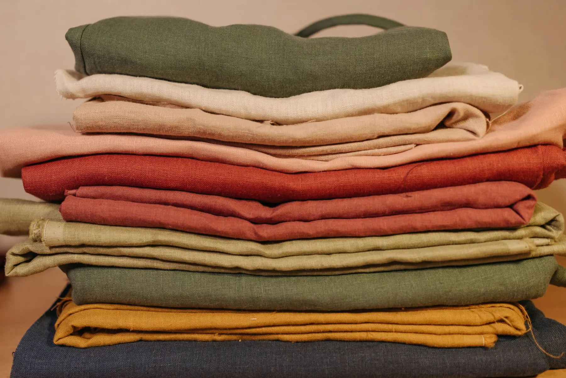 Stack of folded fabrics in green, cream, rust and mustard