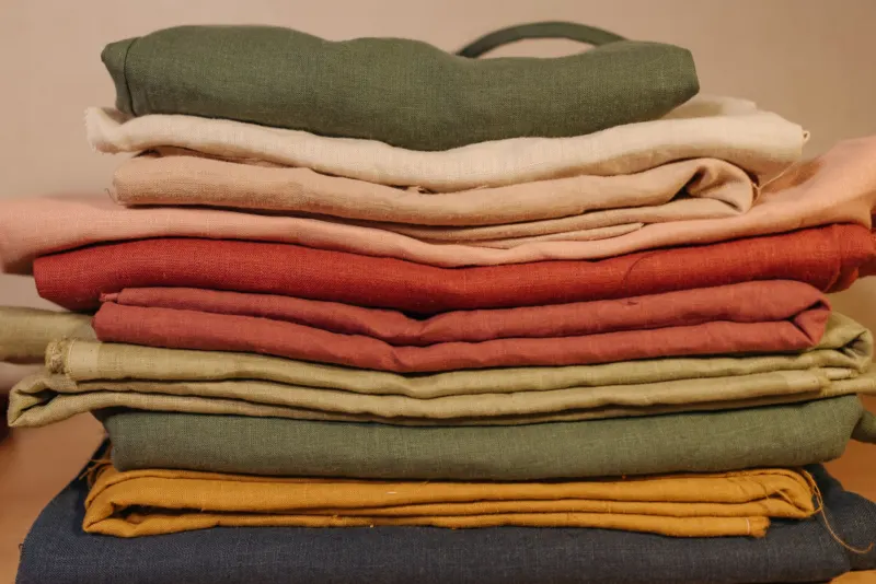 Stack of folded fabrics in green, cream, rust and mustard
