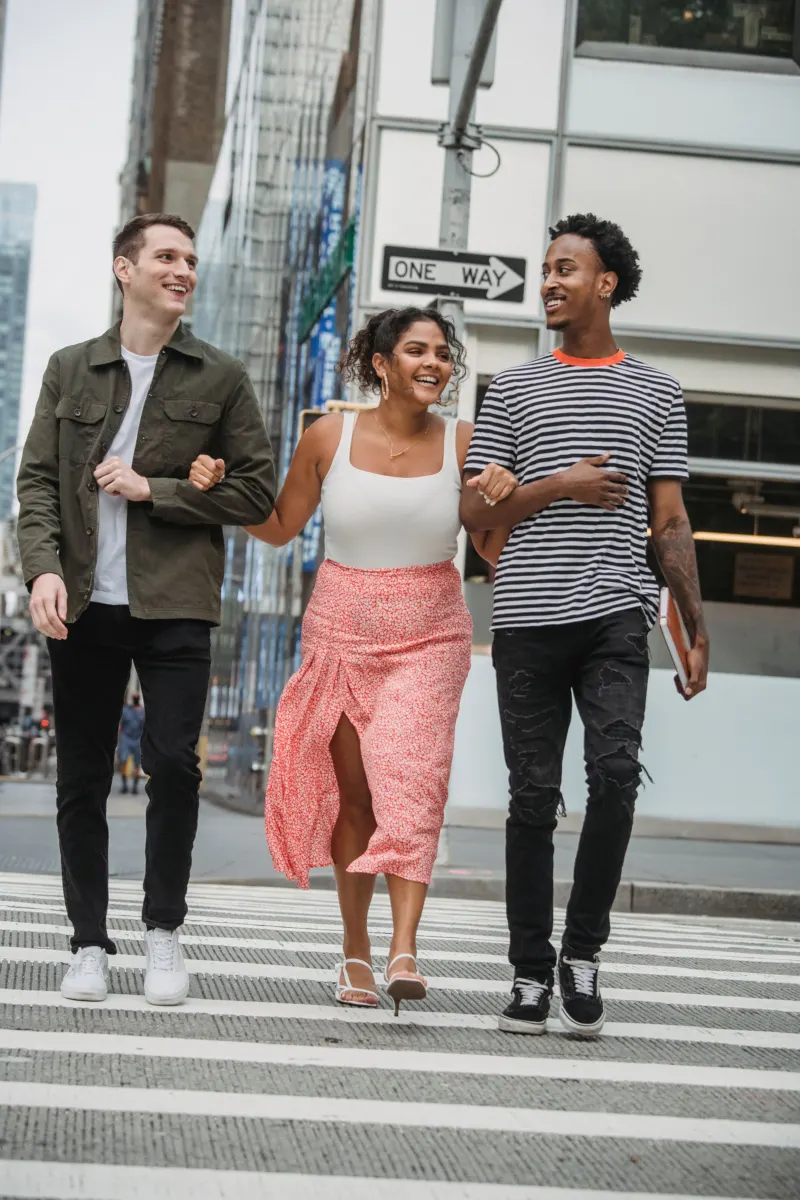Three friends in casual clothes crossing a street together