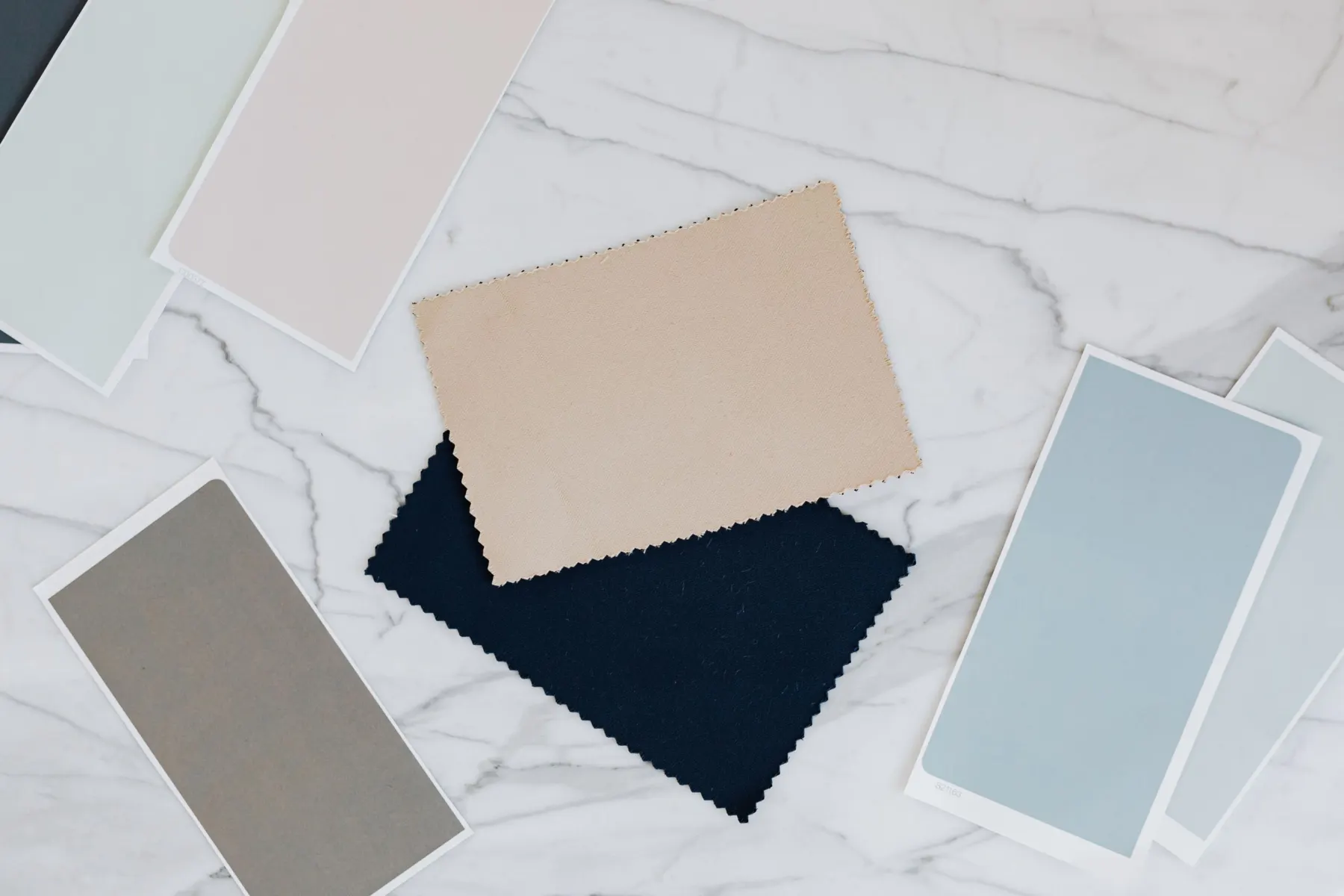 Fabric swatches in beige, navy, grey and pale blue on a marble surface