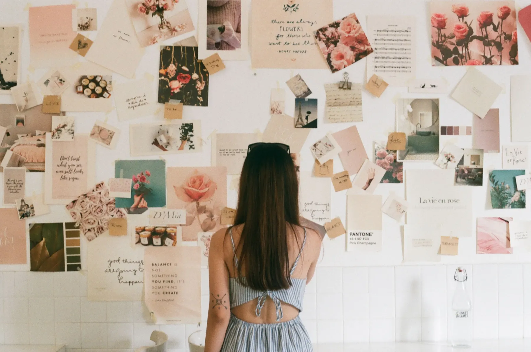 Person facing a wall covered with pinned pictures and notes