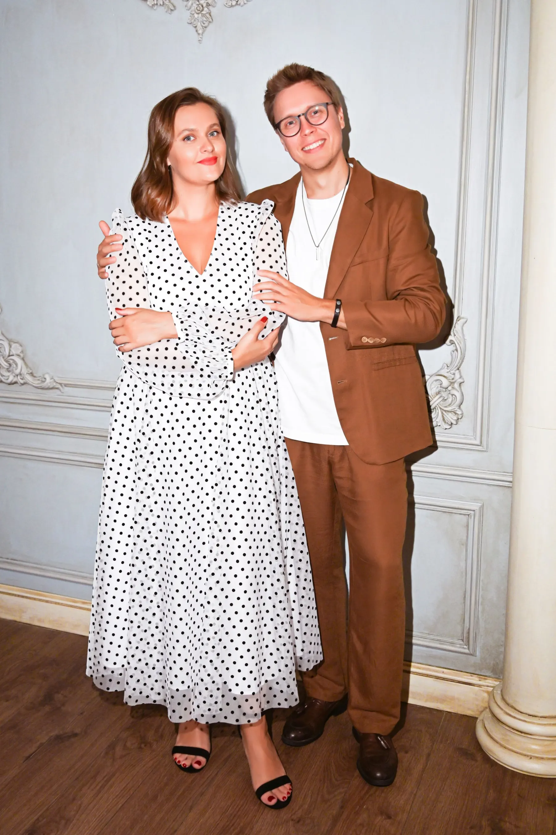 Couple dressed for an occasion in a polka-dot dress and a brown suit
