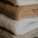 Stack of folded knitwear in cream and tan