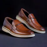 Pair of brown leather loafers on a dark surface