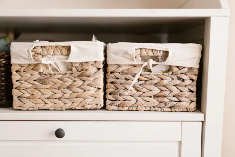 Two woven baskets with fabric liners on a white shelf