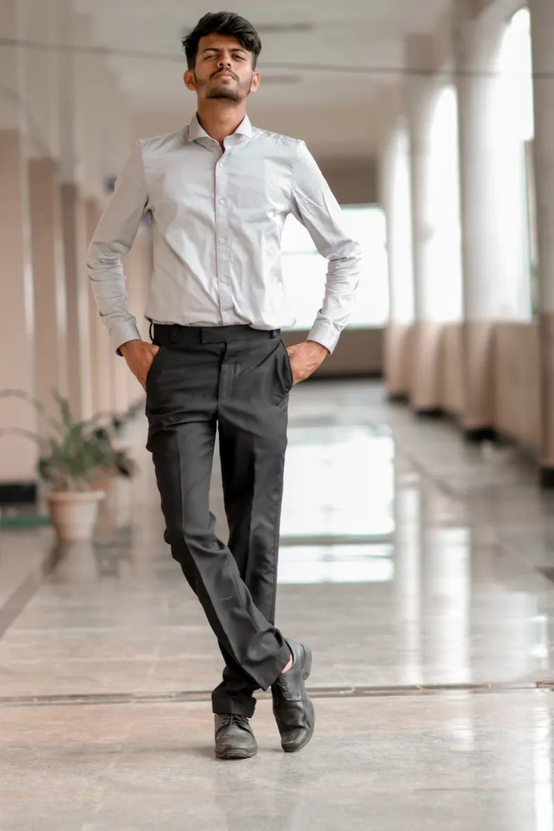 Man in a pale shirt and dark trousers walking along a corridor