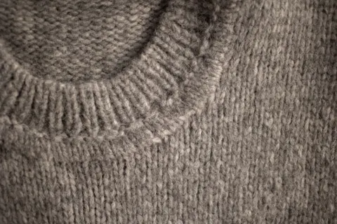 Close-up of a grey knitted jumper at the neckline